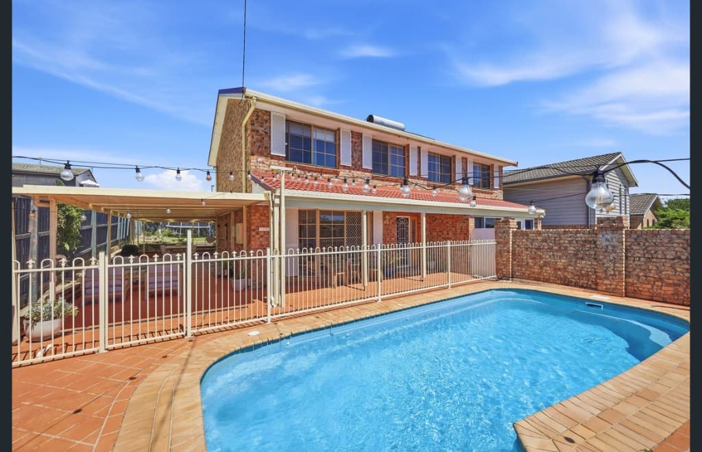 Swimming pool, covered outdoor living, and two-storey brick home at Watonga Coastal Retreat — Lighthouse Beach, Port Macquarie