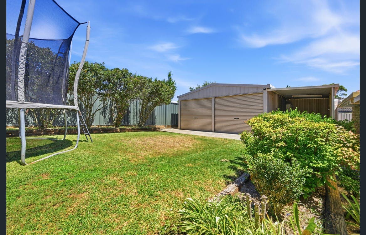 Fully fenced backyard lawn with plenty of room to play, plus a trampoline for the kids